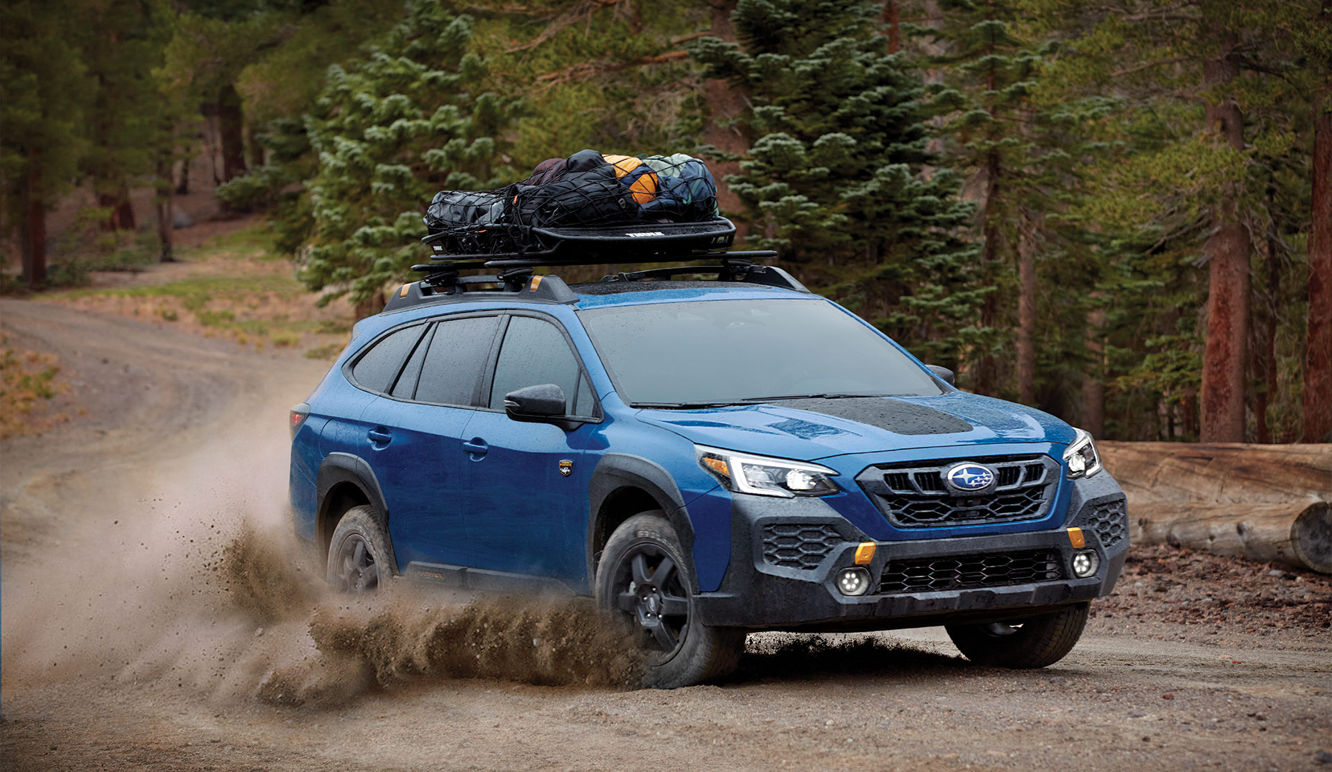 2025 Subaru Outback Wilderness 2025 Outback Wilderness driving on gravel road with cargo basket on the roof.